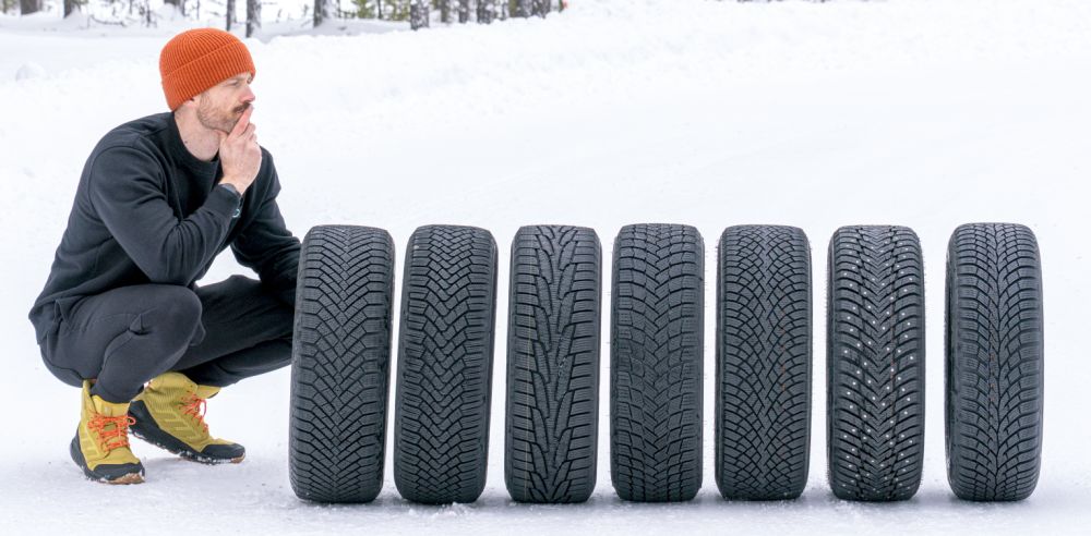 Jonathan Benson på huk bredvid en rad vinterdäck på snö