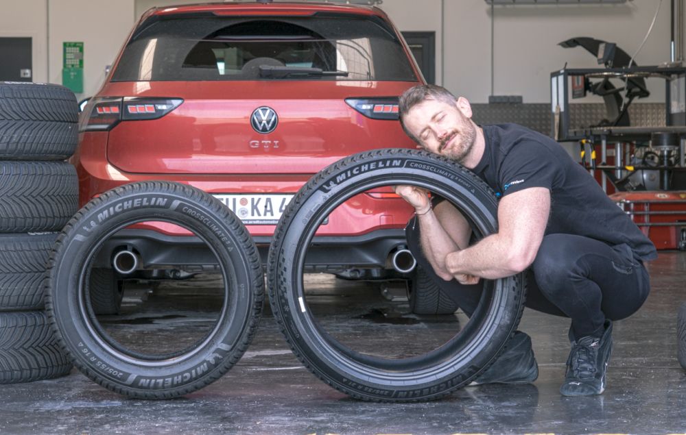 Jonathan Benson med två Michelin-däck framför en Volkswagen Golf GTI som testbil