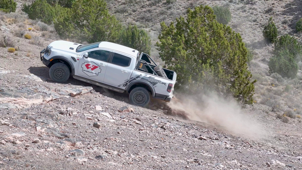 Vit Ford Ranger Raptor som klättrar uppför en stenig sluttning vid Five Mile Pass, med damm bakom bakhjulen
